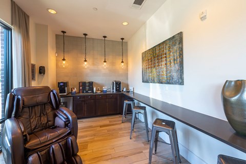 A brown leather chair is in the foreground of a well-lit room with a bar and a painting on the wall.