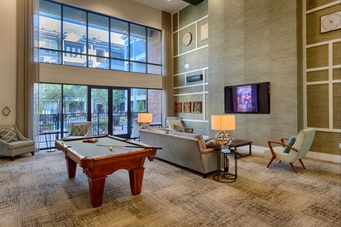 A room with a pool table, couch, and television.