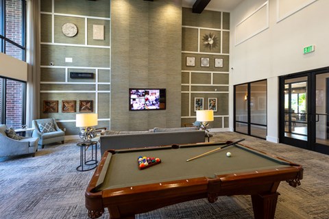 A pool table is in the middle of a room with a couch and a television.