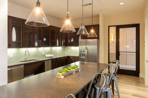 A modern kitchen with a long island and pendant lights.
