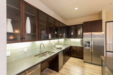 A modern kitchen with dark wood cabinets and stainless steel appliances.