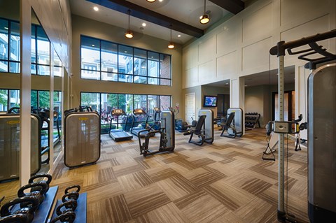 A gym with a variety of equipment including treadmills, weights, and exercise machines.