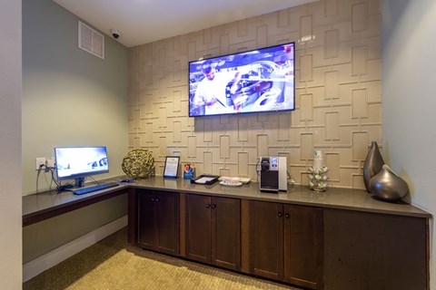 A reception area with a TV mounted on the wall and a desk with a computer and other items.