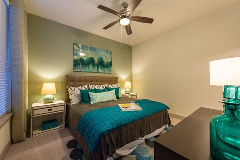 A bedroom with a bed, nightstands, and a ceiling fan.