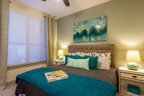 A bedroom with a bed, nightstands, and a painting on the wall.