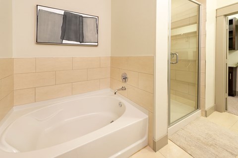 A white bathtub in a bathroom with a glass shower door.