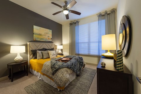 A bedroom with a bed, two lamps, and a ceiling fan.
