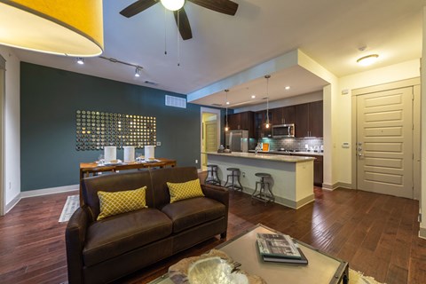 A living room with a brown couch and a ceiling fan.
