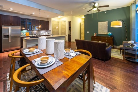 A modern dining room with a wooden table set for two.
