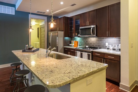 A kitchen with granite countertops and dark wood cabinets.