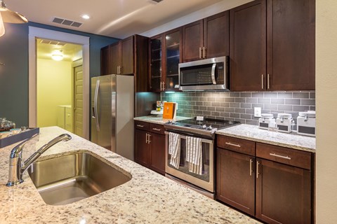A kitchen with brown cabinets and a stainless steel sink.