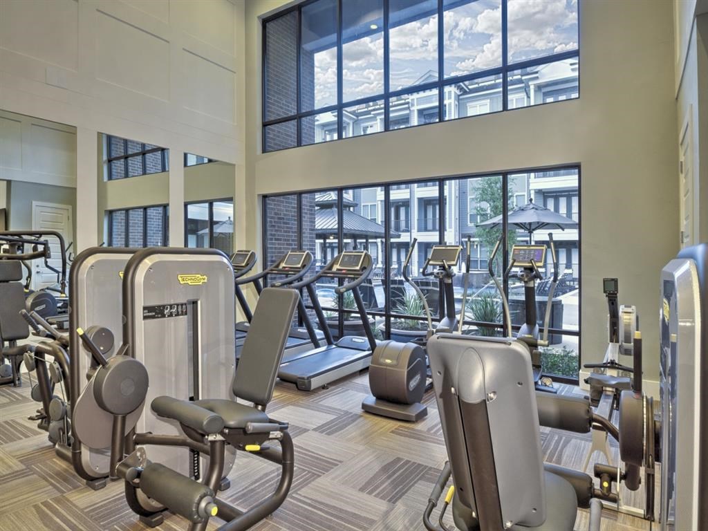 a gym with cardio equipment and windows in a building