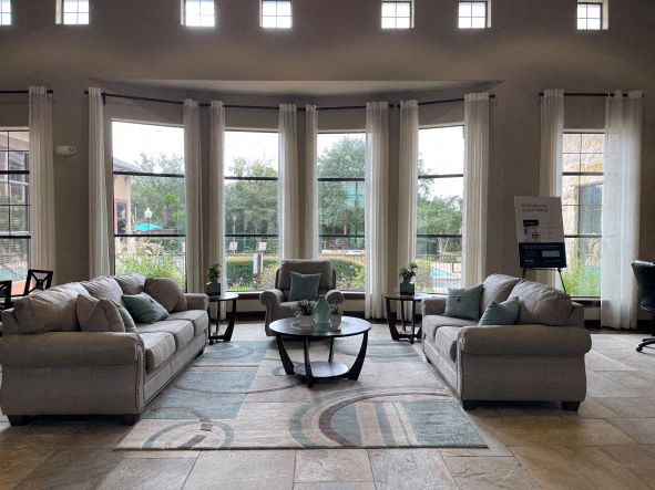 a living room with couches and chairs and windows