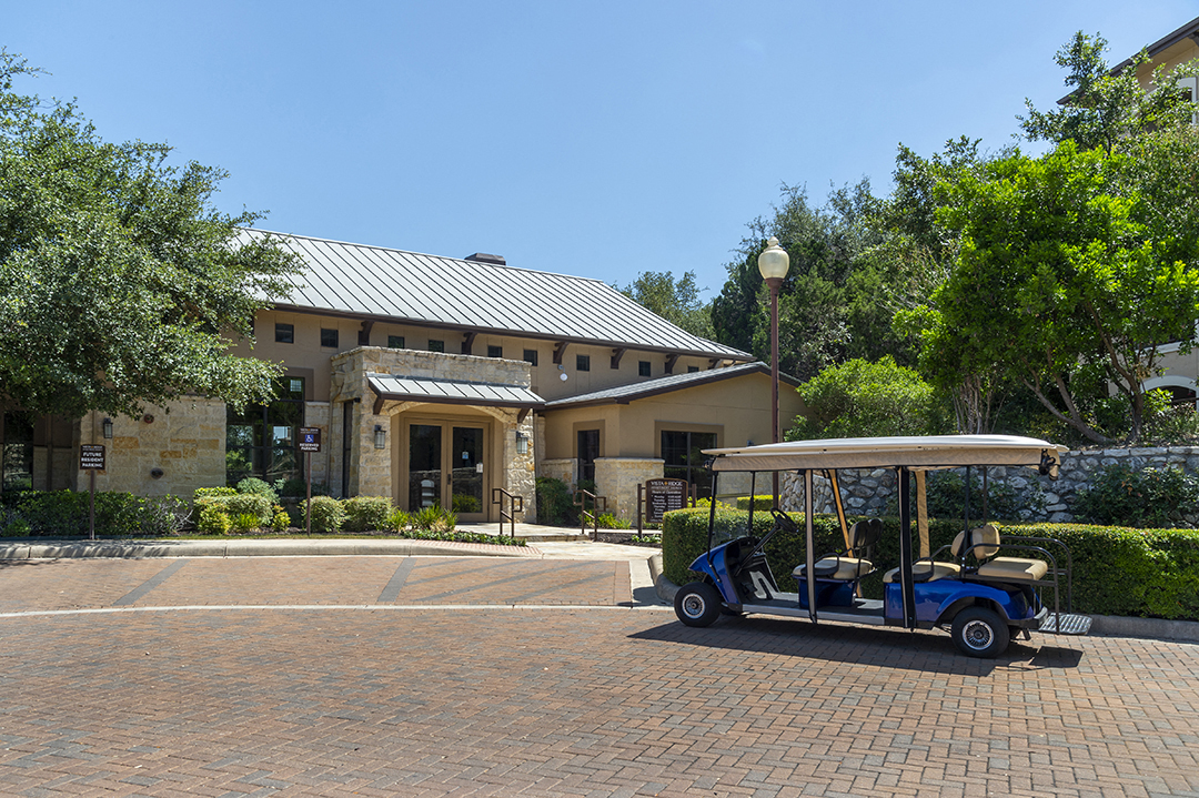 A golf cart is parked in front of a building with a stone facade.