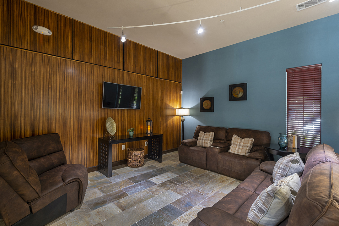 A living room with brown leather furniture and a flat screen TV mounted on the wall.