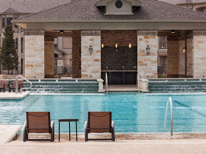 a swimming pool with two chairs in front of a building