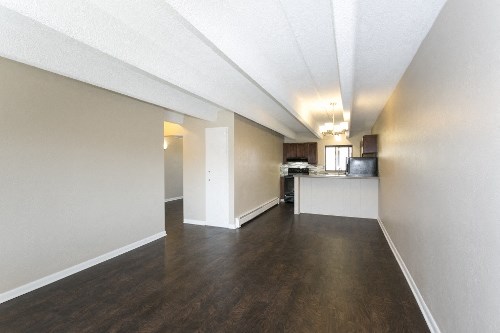 the spacious living room and kitchen of an apartment