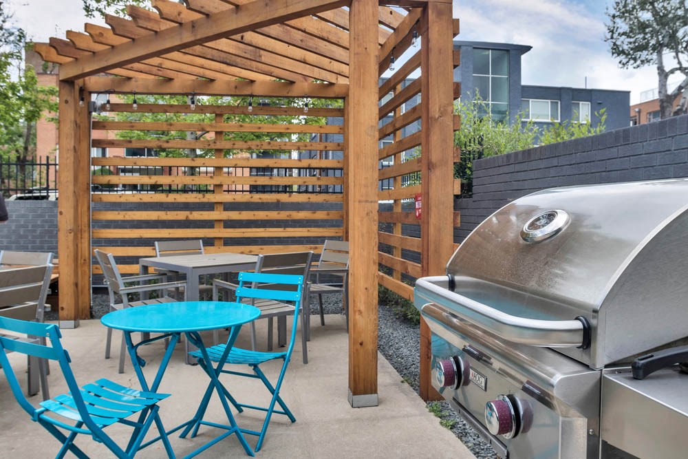 a patio with tables and chairs and a barbecue grill