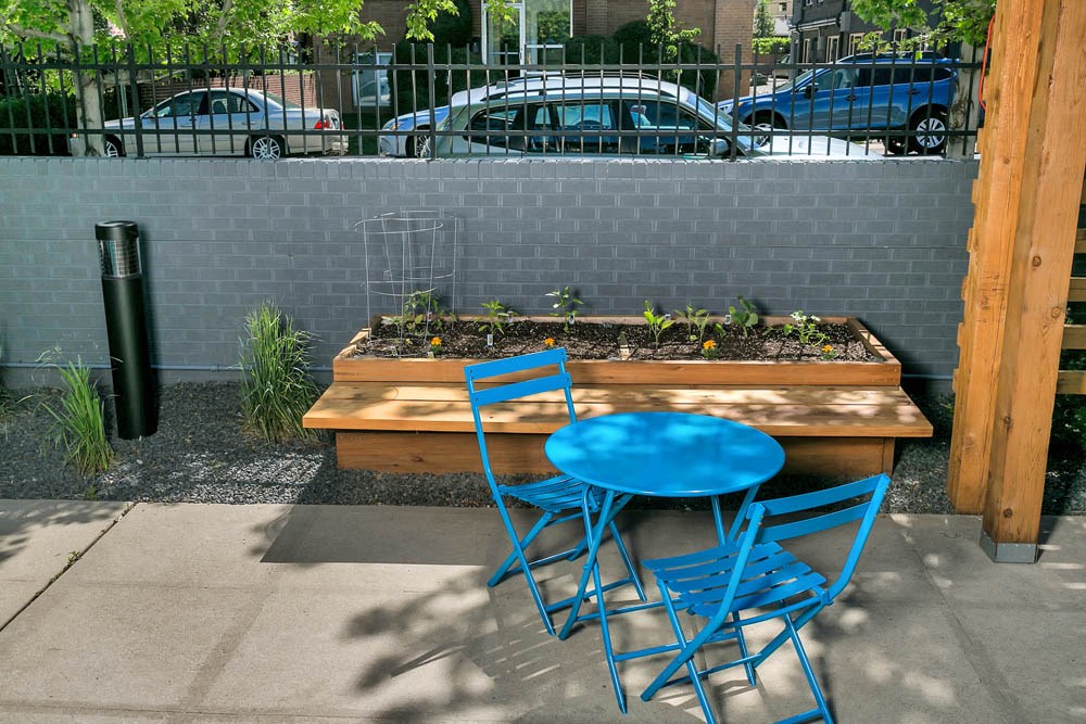 a patio with blue chairs and a table and plants