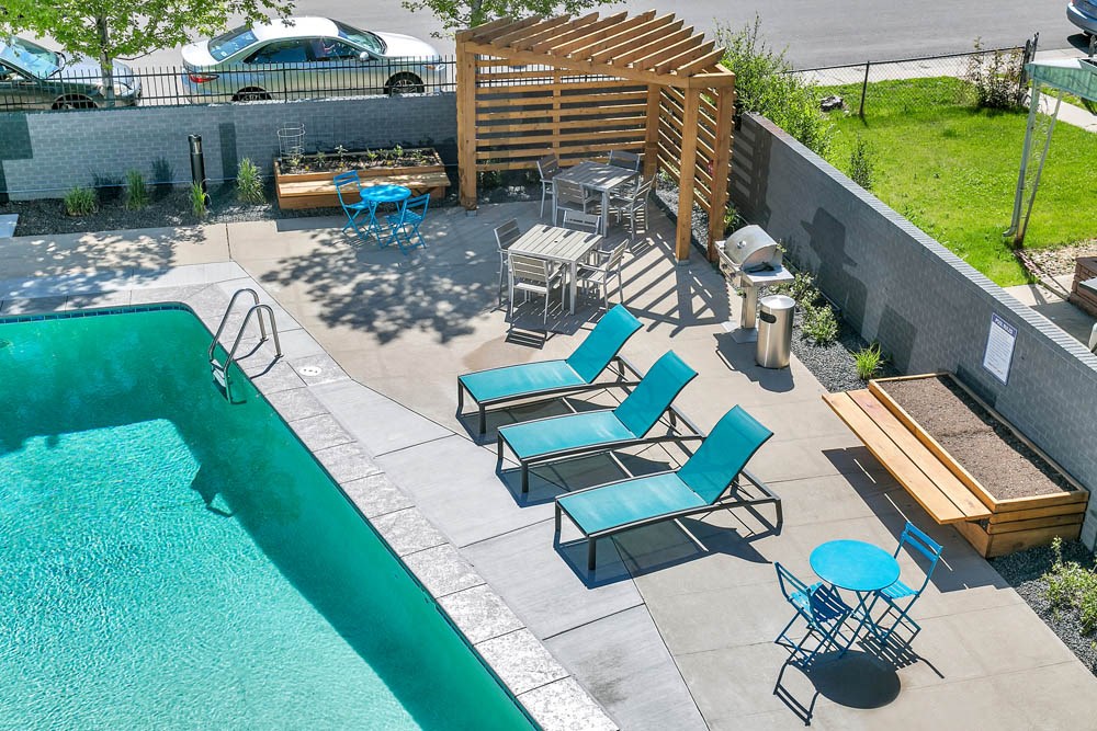a pool and patio with chairs and a table in a backyard