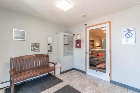 A room with a bench and a door leading to a living room.