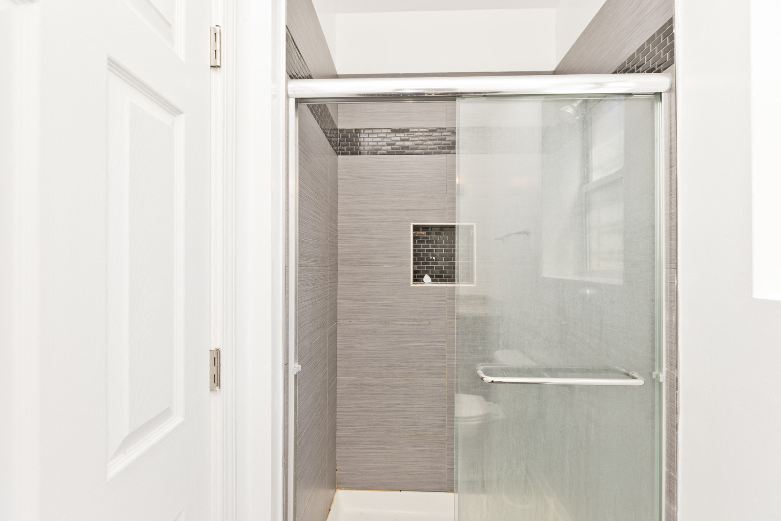 a bathroom with a shower and a white door