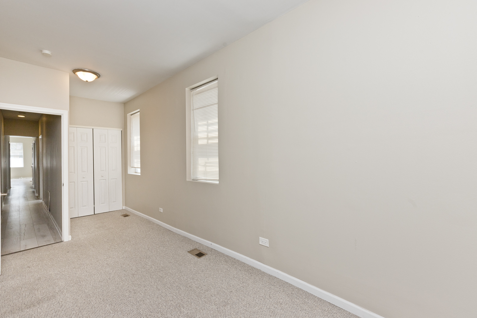 an empty living room with white walls and a door to a hallway