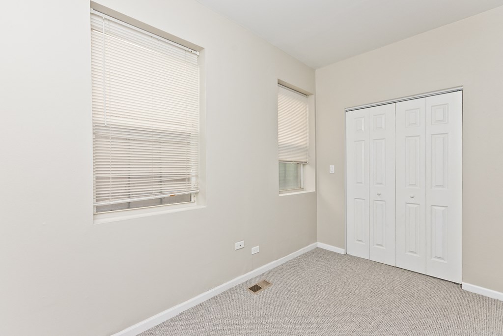 an empty bedroom with two windows and a door