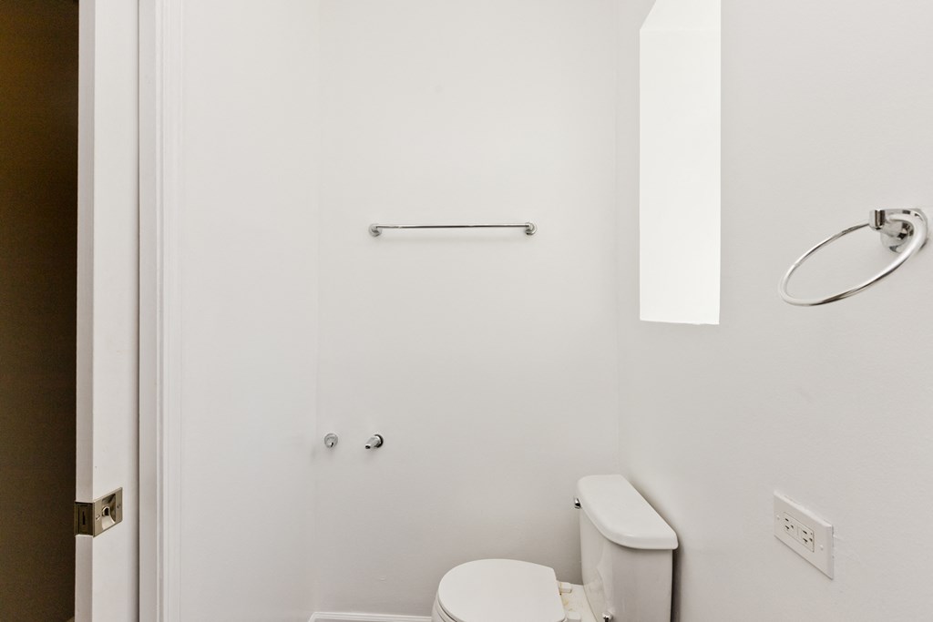 a white bathroom with a toilet and a towel rack