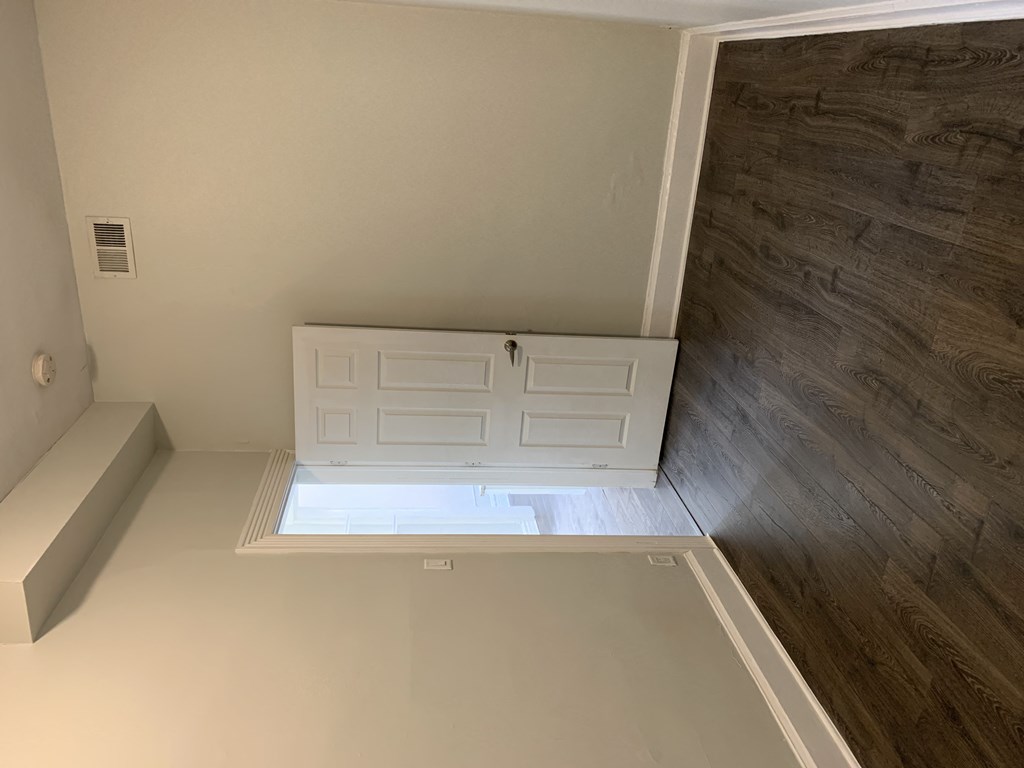 a garage door opens up to a room with a wooden floor and a bench