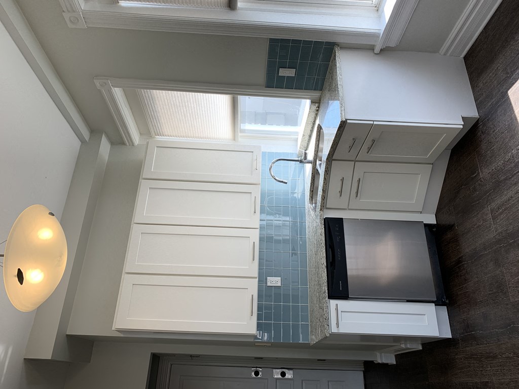 a small bathroom with white cabinets and a window
