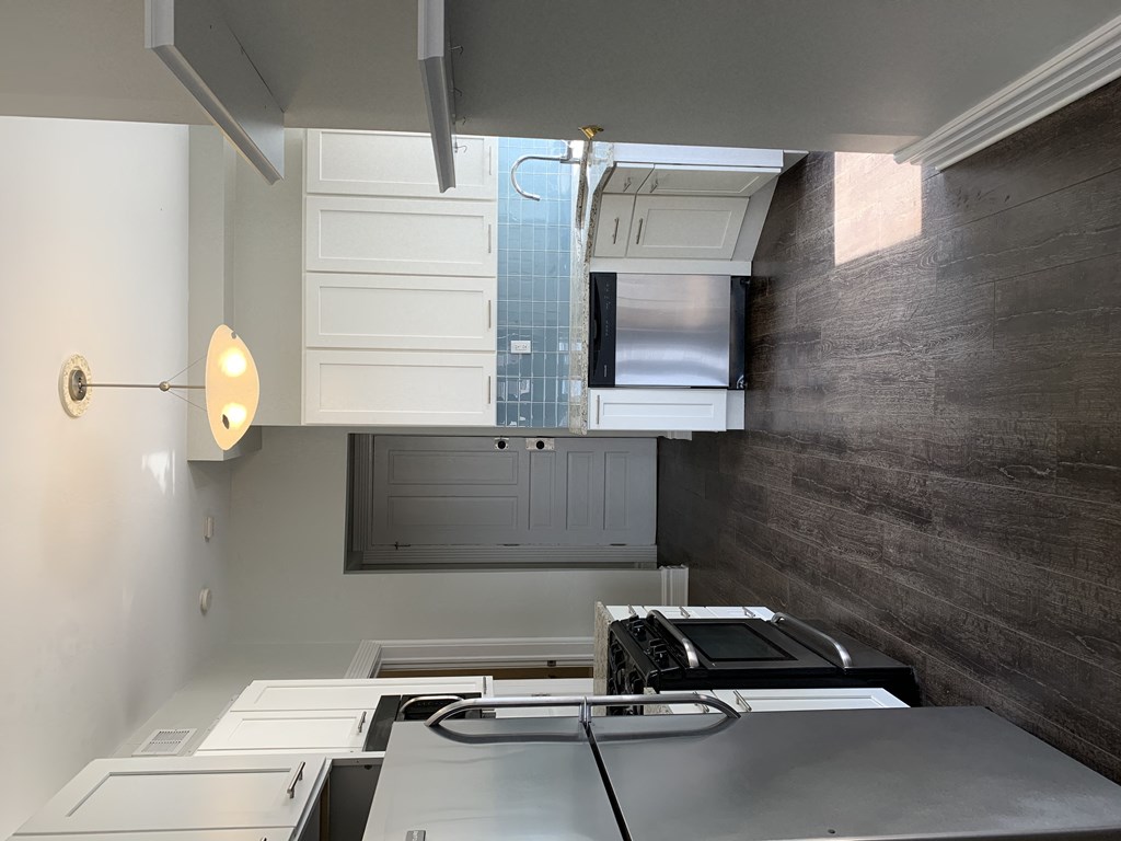 a kitchen with white cabinets and a sink and a window