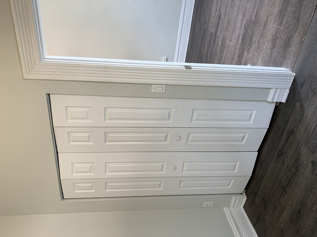 a closet with white drawers and a window