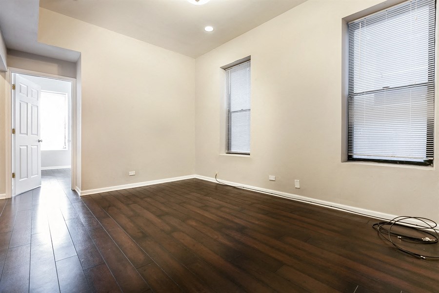 an empty living room with wood flooring and two windows
