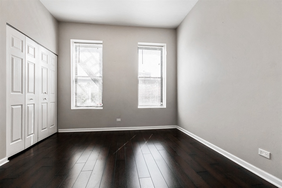 an empty living room with wood floors and two windows