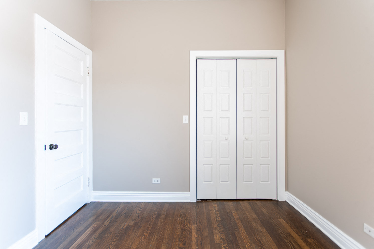 a bedroom with two white doors and wood floors