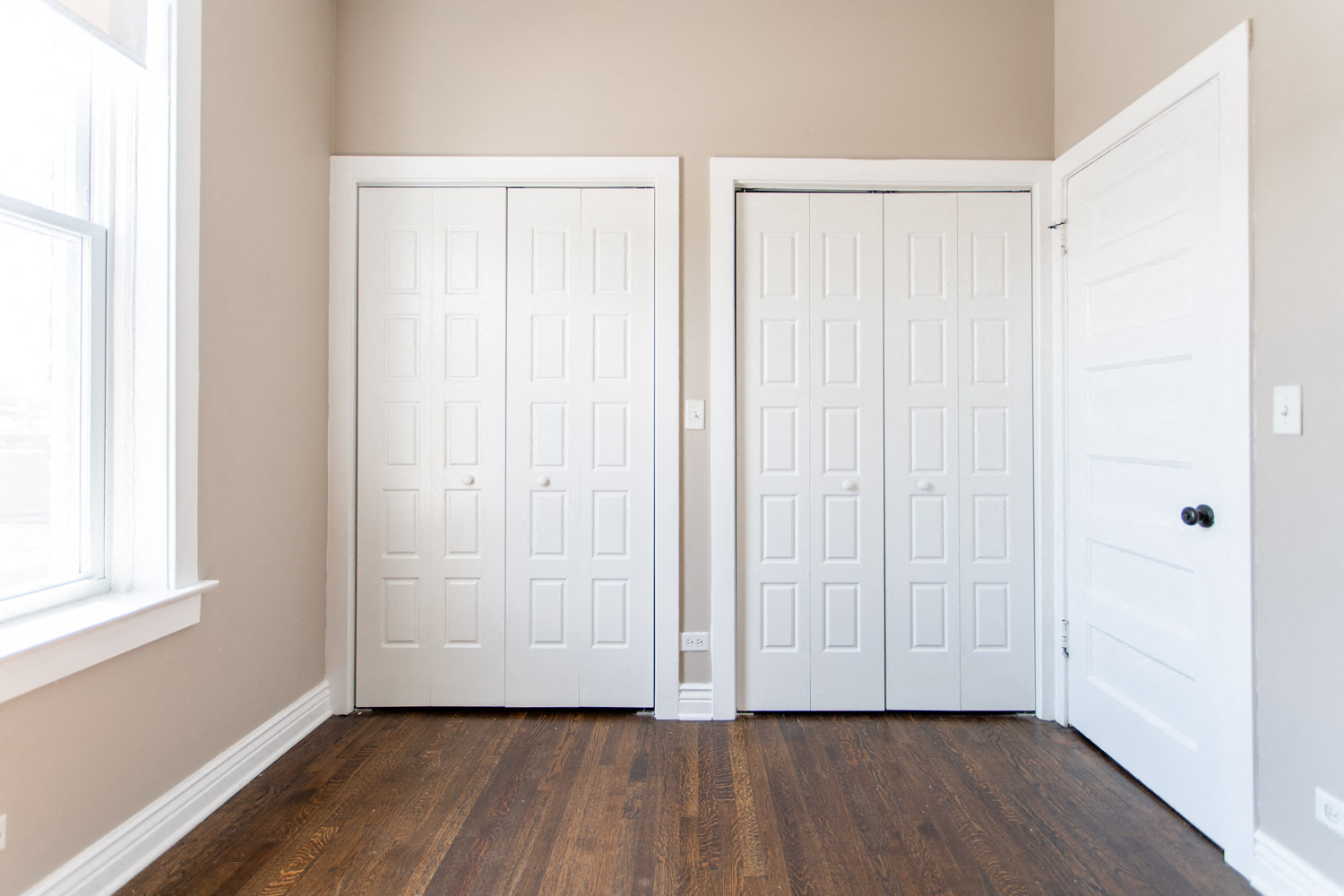 a room with two white doors and a wood floor