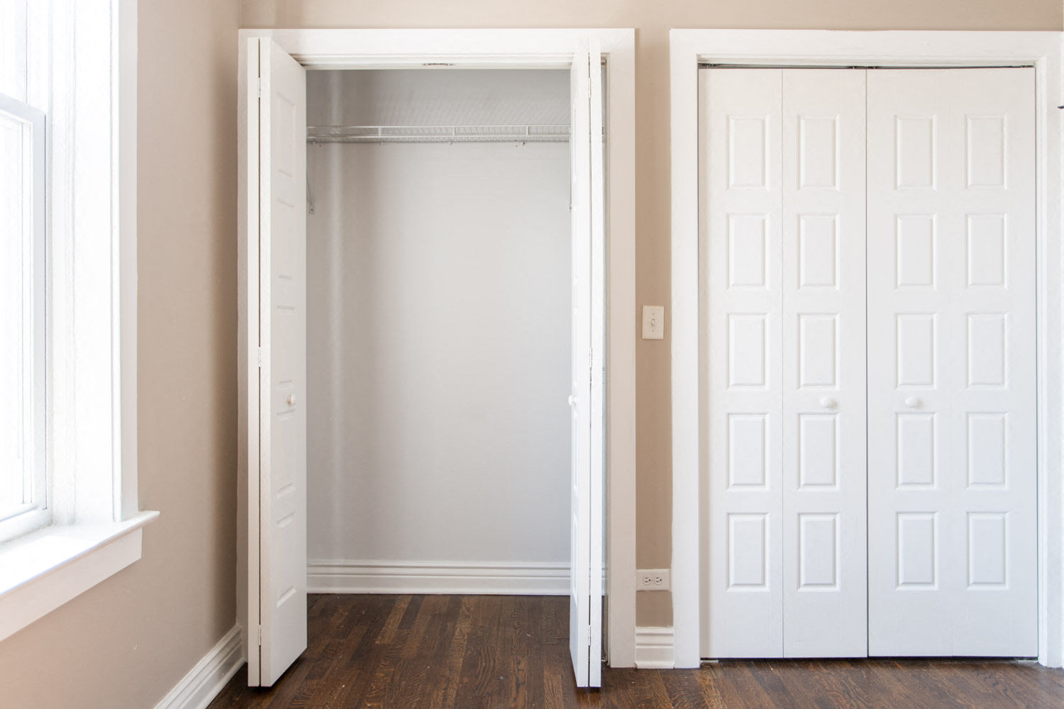 a room with two closets and a wood floor and white doors