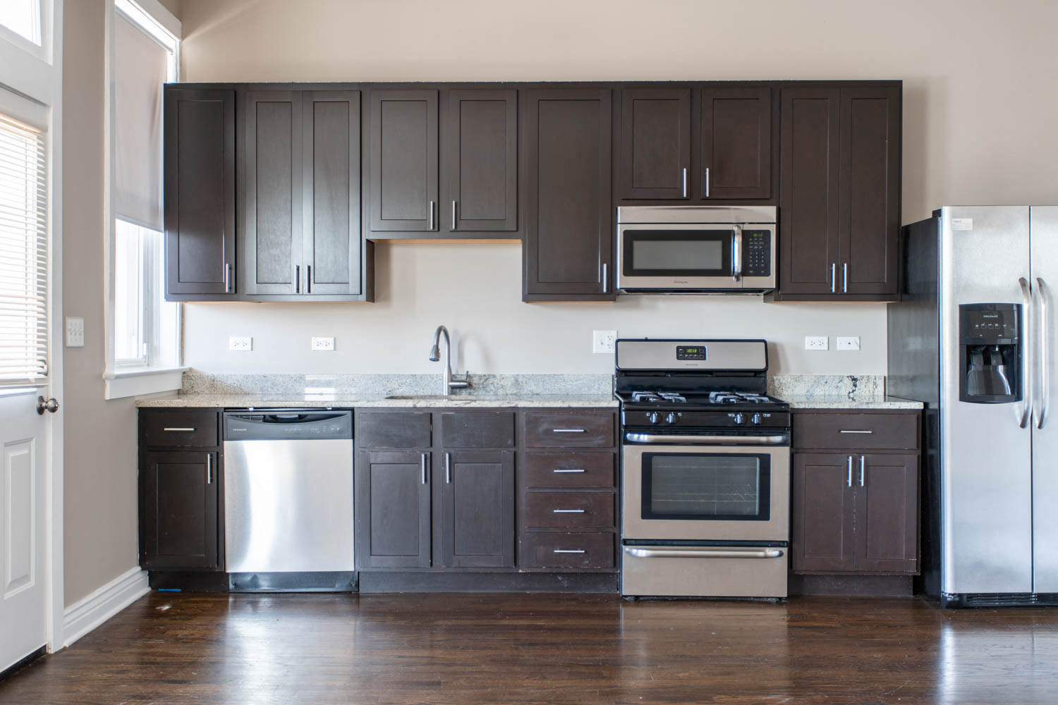a kitchen with dark wood cabinets and stainless steel appliances