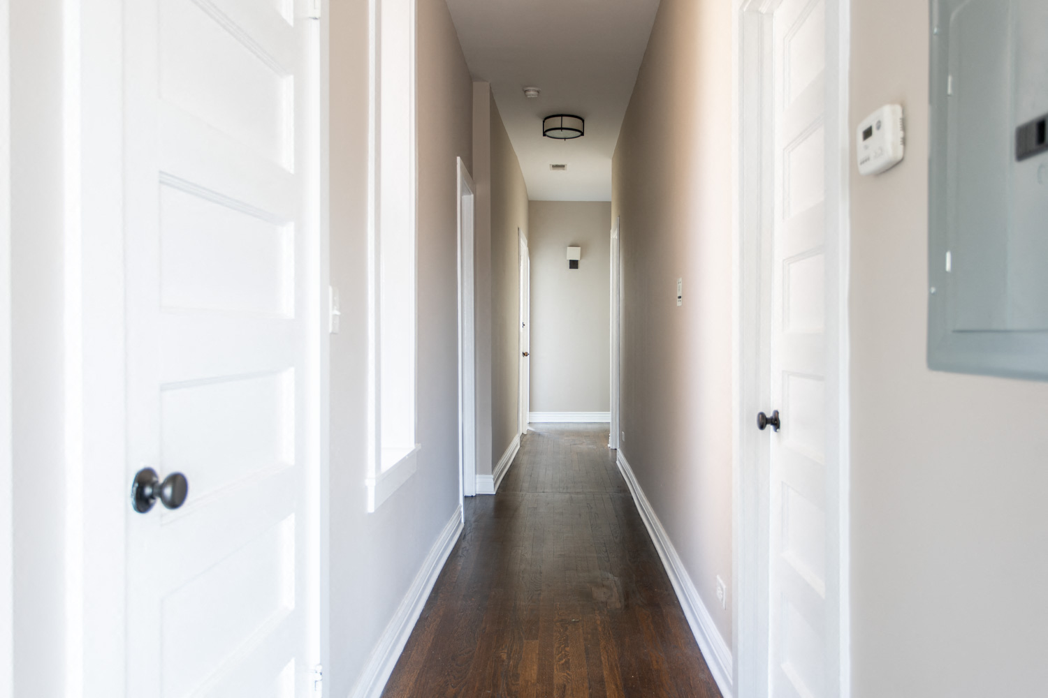 a hallway with white doors and white walls and a wood floor