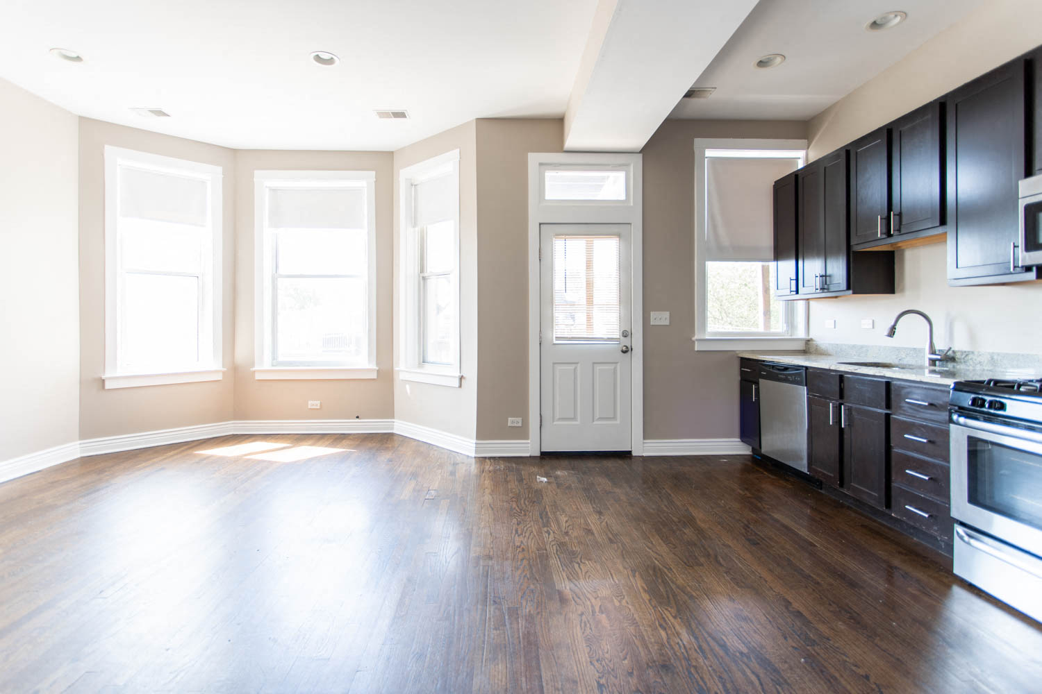 an empty kitchen with black cabinets and stainless steel appliances