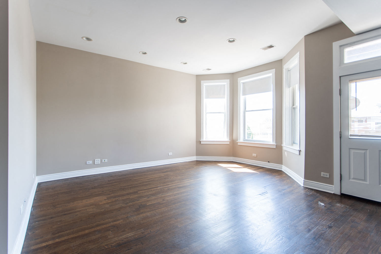 an empty living room with wood floors and windows