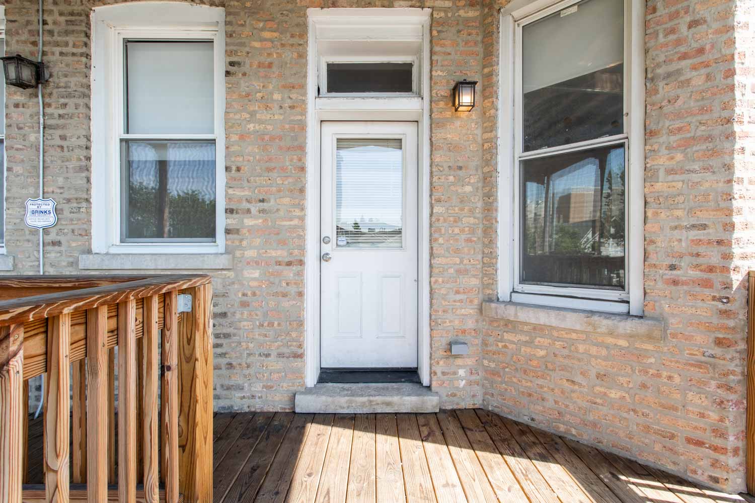 the front porch of a brick house with a white door
