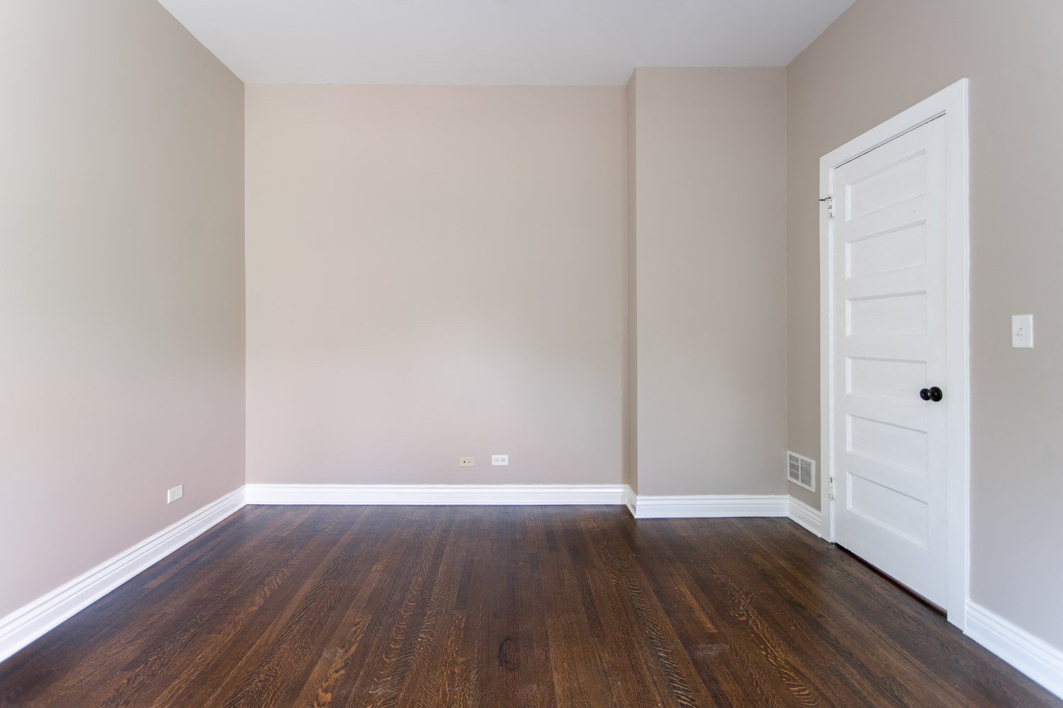 a empty room with wooden floors and a white door