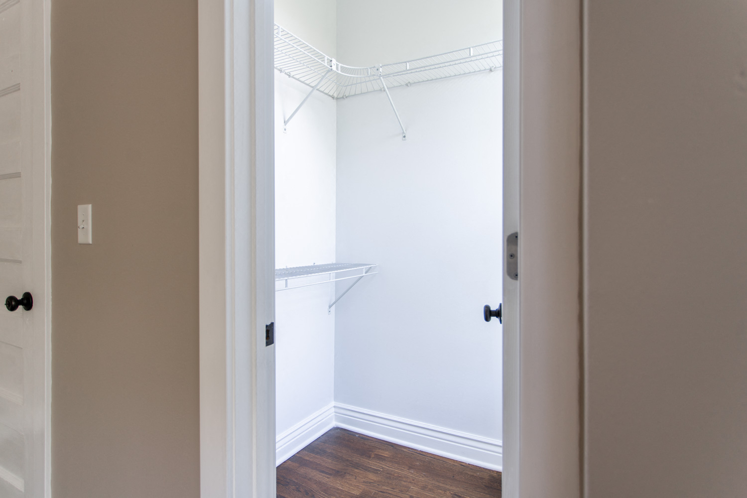 an empty closet in a home with white walls and wood floors
