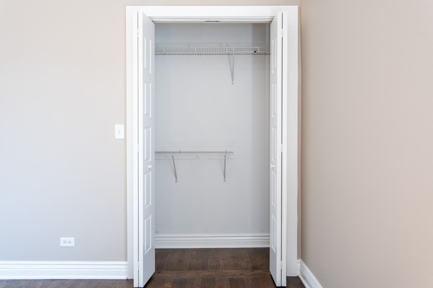 an empty closet in a home with white walls and wood floors