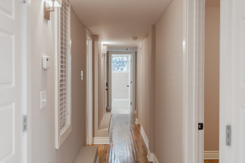 a hallway with white walls and a white door with a window