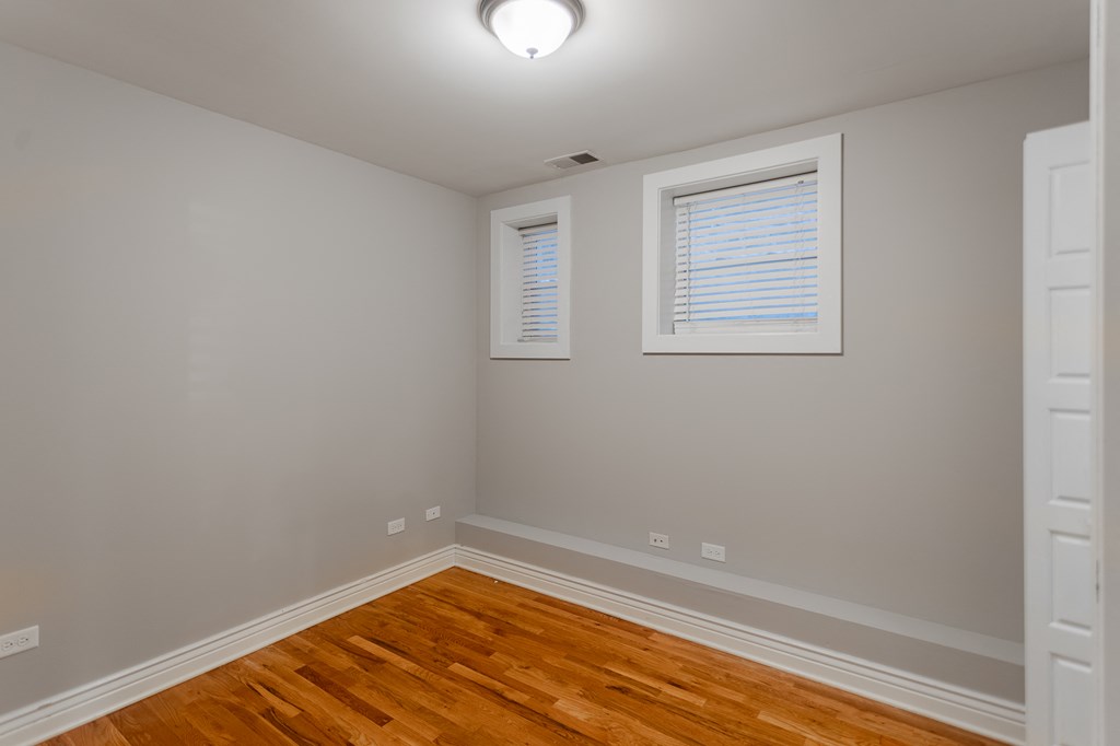 a bedroom with a hard wood floor and a window