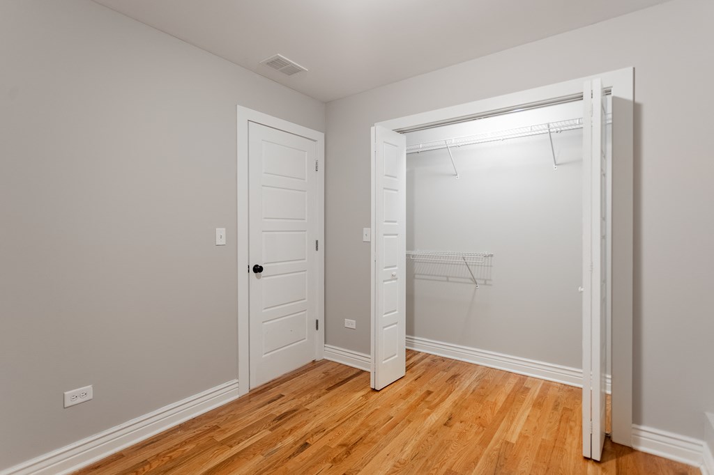 an empty bedroom with a closet and a wood floor