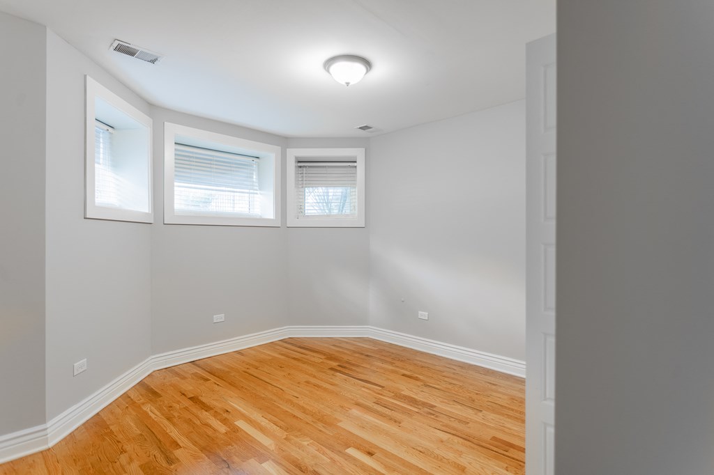 an empty room with a wooden floor and two windows